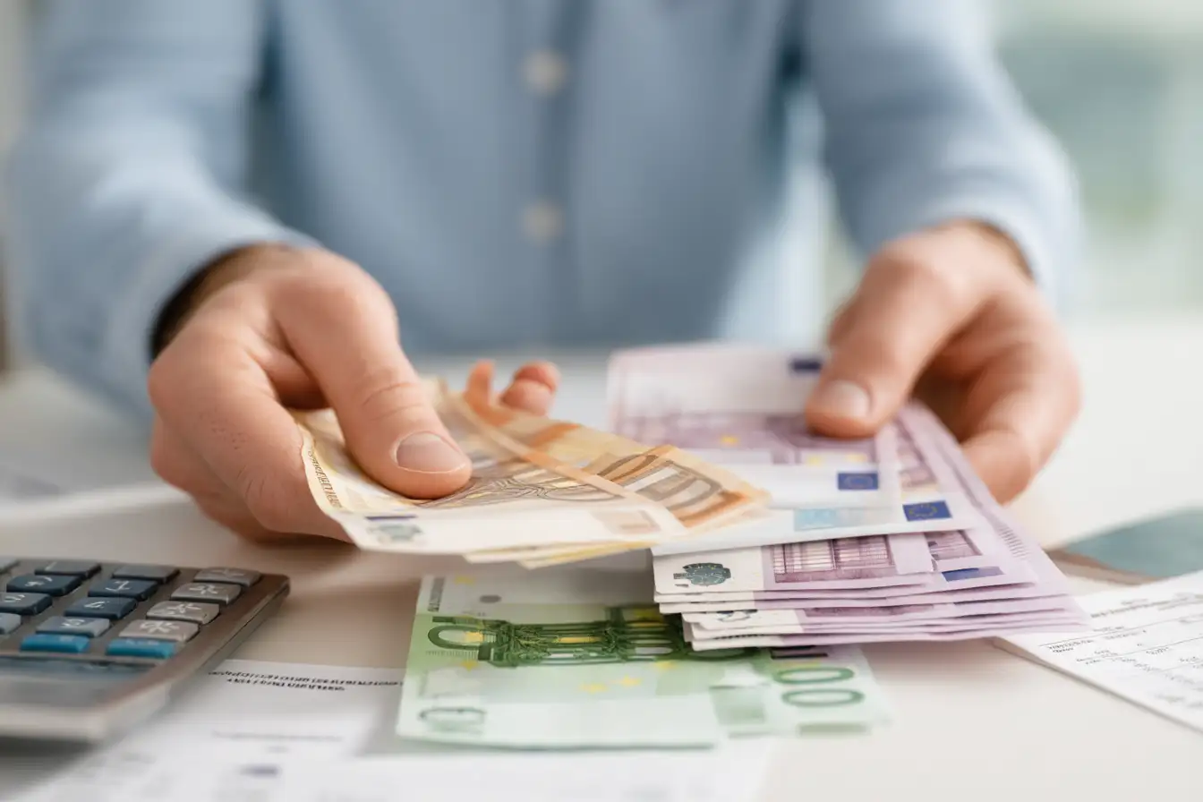 Person zählt Euro-Geldscheine mit Taschenrechner